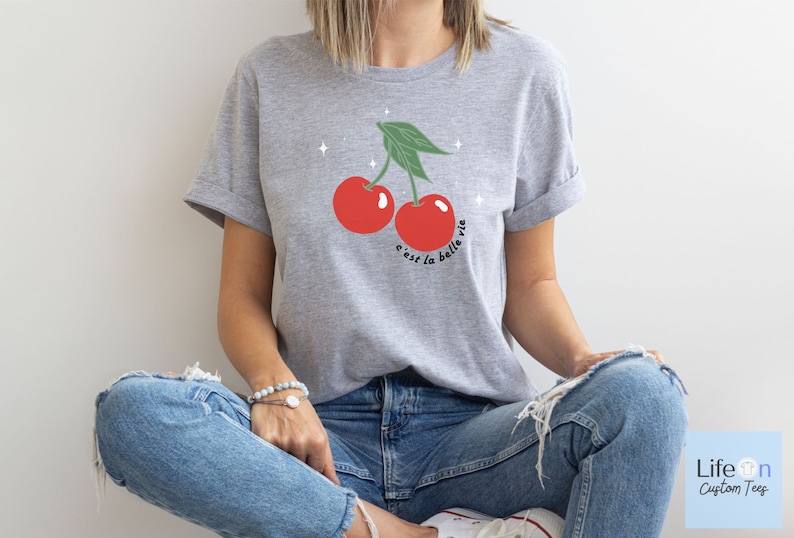 May include: A gray t-shirt with a graphic of two red cherries and the text "c'est la belle vie".