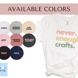 May include: A white t-shirt with the text "never. enough. crafts." in rainbow colours. The shirt is available in 10 colours: white, athletic heather, soft cream, pink, heather mauve, dark grey heather, black, navy, and more.