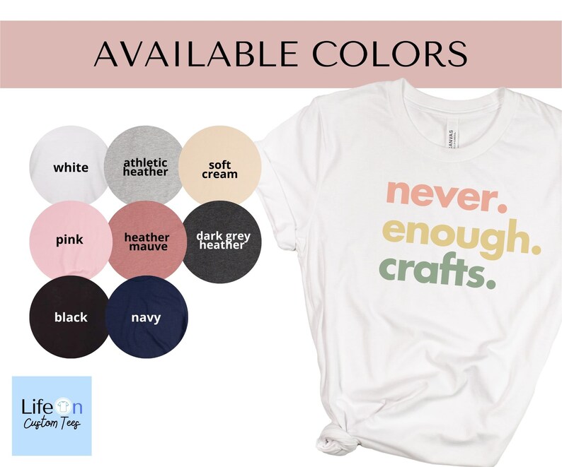 May include: A white t-shirt with the text "never. enough. crafts." in rainbow colours. The shirt is available in 10 colours: white, athletic heather, soft cream, pink, heather mauve, dark grey heather, black, navy, and more.
