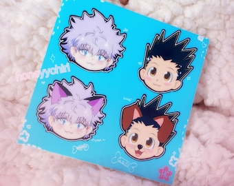 May include: A square, light blue sticker sheet with four anime-style character faces. Two characters have spiky black hair, and two have lavender hair, one with cat ears. The sheet has the text "honeyychiri", "Woof!", "Nyaa~", and "Gon".