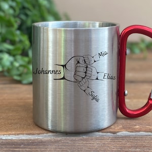 Peut inclure: Mug de voyage en acier inoxydable avec une poignée de mousqueton rouge. Le mug présente un motif de quatre mains jointes avec les noms Johannes, Mia, Elias et Sofia gravés dessus.