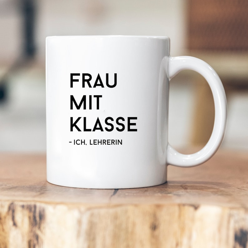 May include: White ceramic mug with black text that reads "FRAU MIT KLASSE - ICH, LEHRERIN".