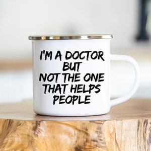 May include: White enamel camping mug with a black inscription that reads "I'm a doctor but not the one that helps people".