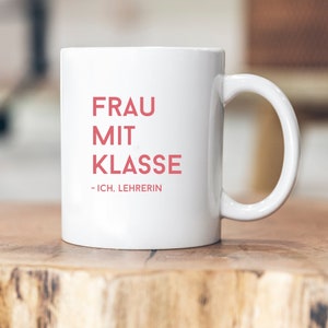 May include: White ceramic mug with the text "FRAU MIT KLASSE - ICH, LEHRERIN" in red.