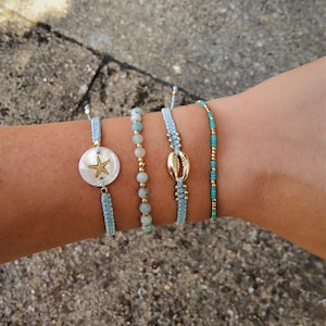 May include: Four blue and turquoise beaded bracelets with gold accents. One bracelet features a seashell charm, another has a starfish charm, and the other two have small gold beads.
