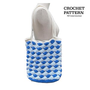Op de afbeelding: Een gehaakte draagtas in blauw en wit met een ruitpatroon. De tas heeft witte hengsels en een witte bovenrand. De tekst "CROCHET PATTERN PDF Instant download" is zichtbaar.