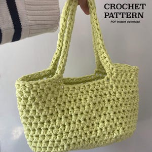 Op de afbeelding: Een lichtgroene gehaakte tote bag met gevlochten handvatten. De tas is gemaakt van dik garen en heeft een textuur. Tekst op de afbeelding luidt "CROCHET PATTERN PDF instant download."