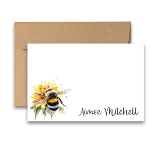 Puede incluir: Una tarjeta blanca con una ilustraci&oacute;n de acuarela de un abejorro en una flor amarilla. La tarjeta tiene el nombre "Aimee Mitchell" impreso en cursiva gris.