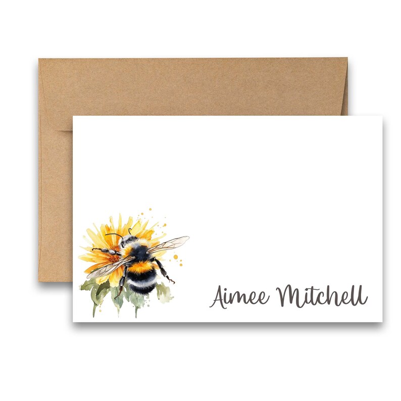 Puede incluir: Una tarjeta blanca con una ilustraci&oacute;n de acuarela de un abejorro en una flor amarilla. La tarjeta tiene el nombre "Aimee Mitchell" impreso en cursiva gris.