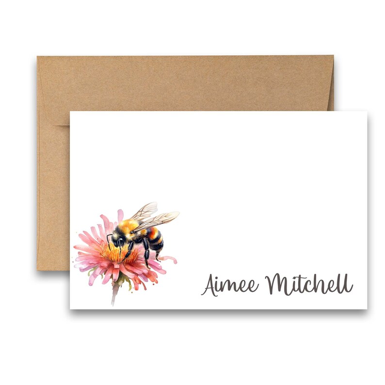 Puede incluir: Una tarjeta blanca con una ilustraci&oacute;n de acuarela de un abejorro en una flor rosa. La tarjeta tiene el nombre "Aimee Mitchell" escrito en cursiva en la parte inferior.