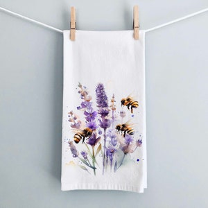 May include: A white kitchen towel with a watercolor illustration of purple lavender flowers and yellow and black bees.