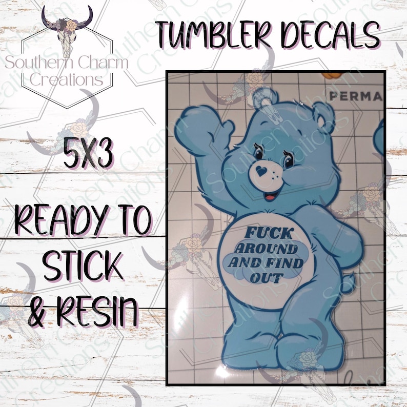 K&ouml;nnte beinhalten: Hellblauer Care Bear-Stil Aufkleber mit dem Text "FUCK AROUND AND FIND OUT" auf dem Bauch. Der Aufkleber ist 12,7 x 7,6 cm gro&szlig; und ist zum Aufkleben und Verharzen bereit. Der Text "Tumbler Decals" steht oben.