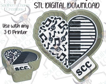 May include: A heart-shaped 3D printer file design featuring a musical theme. The left side displays black musical notes on a white background, while the right side shows black piano keys. The text "SCC" is visible on a small tab. The file is labeled "Freshie Housing STL DIGITAL DOWNLOAD" and "Use with any 3-D Printer".