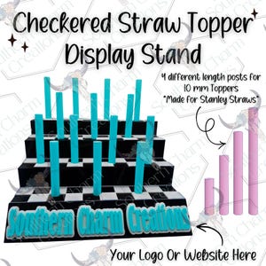 Op de afbeelding: Een zwart-wit geblokte displaystandaard voor strohalmtoppers. De standaard heeft meerdere niveaus met turquoise palen. De tekst op de standaard luidt "Checkered Straw Topper Display Stand" en "Southern Charm Creations". Inclusief roze palen voor 10 mm toppers.
