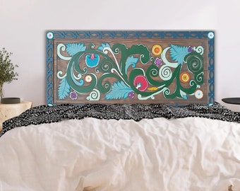 May include: A wooden headboard with a hand-painted floral design. The design features green, blue, pink, and orange flowers and leaves on a brown background. The headboard is framed with a blue border and is placed above a bed with white bedding.