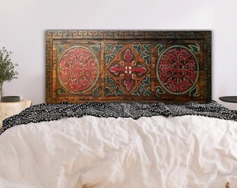 May include: A wooden headboard with three carved panels featuring intricate geometric designs in shades of red, green, and brown. The headboard is a decorative accent for a bedroom.