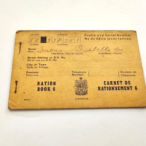 Può includere: Un libretto di razionamento canadese vintage, Libro 6, con il nome "Irons" e il nome "Isabelle M" scritti a mano. Il libro è color cachi con testo nero e uno stemma canadese. Il testo include "Prefix and Serial Number" e "Carnet de Rationnement 6".