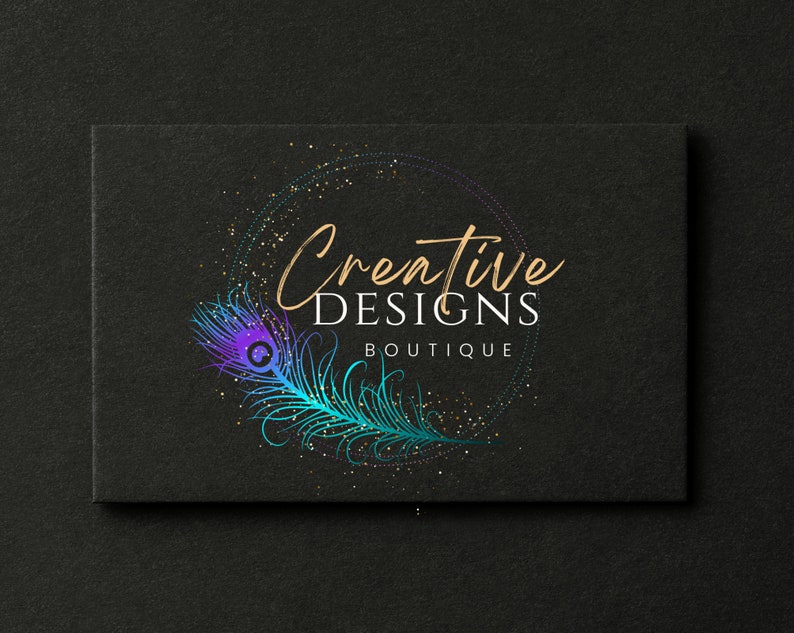 May include: A black and gold logo with the text "Creative Designs Boutique" in a white font. The logo features a peacock feather with blue, purple, and green colors.