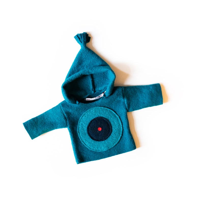 May include: Teal hooded sweatshirt with a large blue and green circle with a black circle in the centre and a red dot.