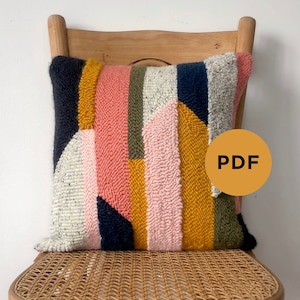 Peut inclure: Un coussin à motif géométrique coloré avec une variété de couleurs, notamment le rose, le jaune, le bleu, le vert et le blanc. Le coussin est posé sur une chaise en bois avec un siège en cannage. L'image comprend le texte "PDF".