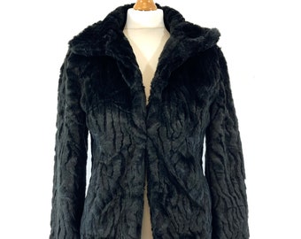 May include: A black faux fur jacket with a collar and a button closure.