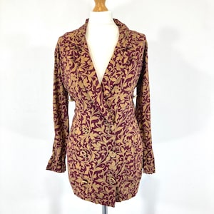 May include: A burgundy blazer with a gold floral pattern and gold buttons. The blazer has a deep V-neck and long sleeves.