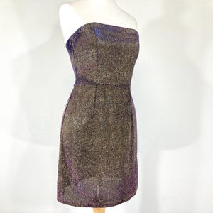May include: A strapless, knee-length dress with a shimmering, textured fabric. The dress features a dark brown base with gold and purple metallic threads, creating a sparkling effect. The dress is displayed on a mannequin.
