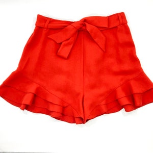 Puede incluir: Shorts rojos con volantes y un lazo en la cintura.
