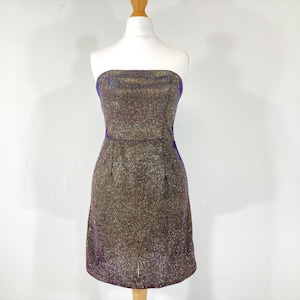 May include: A strapless, knee-length dress with a shimmering gold and purple fabric. The dress is displayed on a mannequin against a white background. The dress has a fitted bodice and a slightly flared skirt, suitable for a party or special occasion.