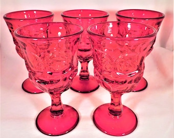 May include: Set of five ruby red glass goblets with a textured design. The goblets have a round bowl and a tall stem.