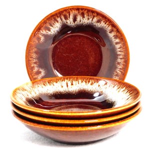 May include: Set of four brown ceramic bowls with a white and brown speckled rim. The bowls are stacked, with one bowl visible on top. The bowls have a glossy finish and a deep, reddish-brown interior.