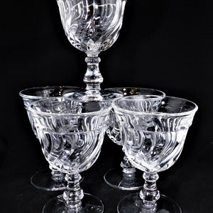 May include: Set of five clear glass wine glasses with a swirl design. The glasses have a tall, slender stem and a wide bowl.
