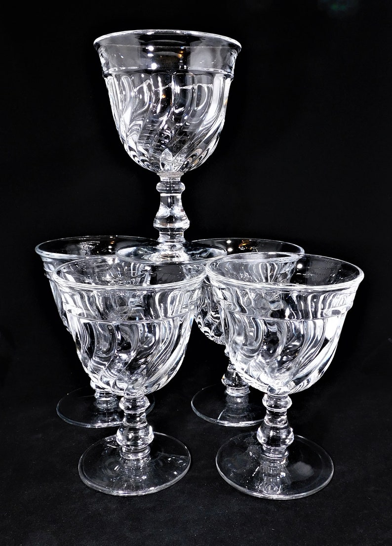 May include: Set of five clear glass wine glasses with a swirl design. The glasses have a tall, slender stem and a wide bowl.