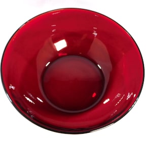May include: A vibrant red glass bowl with a glossy finish. The bowl has a rounded shape with a wide opening and a dark rim. The interior of the bowl reflects light, creating highlights and shadows.