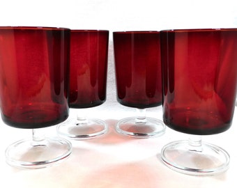 May include: Set of four red glass goblets with clear glass stems and bases. The goblets are all the same size and shape.