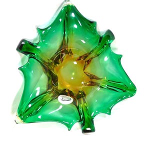 May include: A decorative glass bowl in a leaf shape, featuring a vibrant gradient of green and yellow hues. The bowl has a glossy finish and a starburst design in the center. The bowl is approximately 8 inches in diameter.