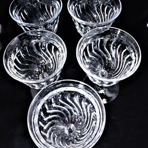May include: Set of six clear glass dessert bowls with a swirl pattern. The bowls are empty and have a stemmed base.