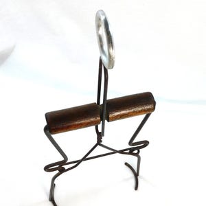 May include: Vintage bottle opener with a dark wooden handle and a silver metal ring. The opener has a wire frame and is designed to remove bottle caps. The wooden handle is a rich brown color.