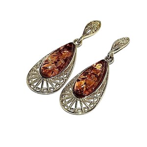 Puede incluir: Un par de pendientes colgantes con una piedra de ámbar en forma de lágrima engastada en un diseño de filigrana de plata.
