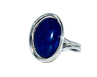 May include: A silver ring with a large oval-shaped lapis lazuli gemstone. The ring has a simple, elegant design.