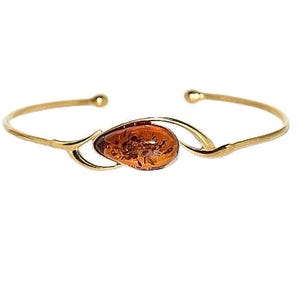 Op de afbeelding: Een gouden armband met een traanvormige amber steen in het midden.