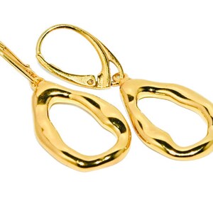 May include: A pair of gold-toned dangle earrings with a textured, irregular oval shape. The earrings have a hook fastening.