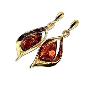 Puede incluir: Un par de pendientes de oro con piedras de ámbar. Los pendientes tienen forma de lágrima y un diseño retorcido.