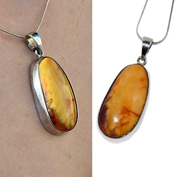An Eastern inspired white metal and butterscotch amber necklace, the oblong  beads of butterscotch amber 2cm