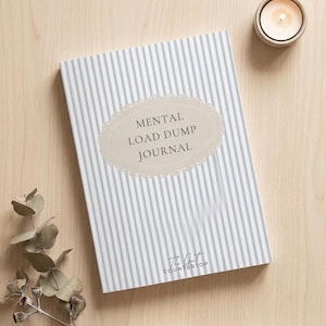 Puede incluir: Un diario con una cubierta de rayas verticales azul claro y blanco que presenta una etiqueta beige festoneada en el centro con el texto MENTAL LOAD DUMP JOURNAL y el texto The Quiet Countertop impreso en letras negras pequeñas abajo.