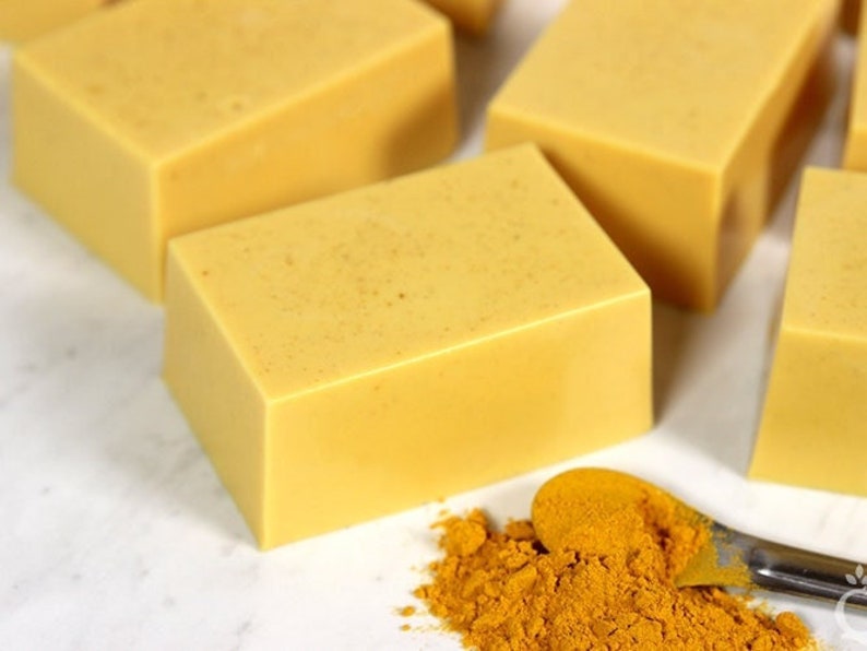 May include: Four bars of yellow soap with a small spoon containing yellow turmeric powder.