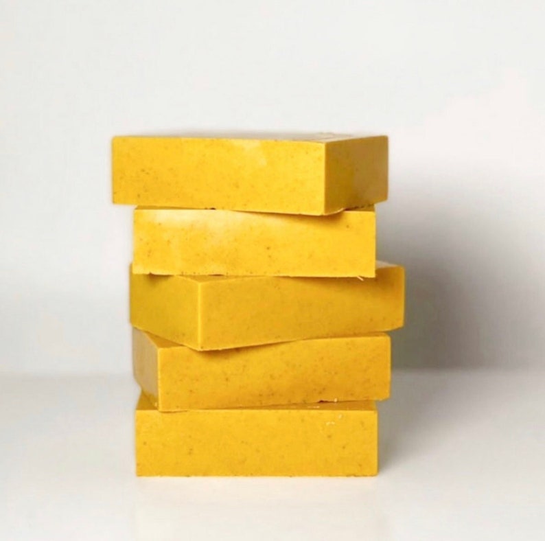 May include: A stack of five yellow soap bars. The bars are rectangular and have a slightly textured surface.