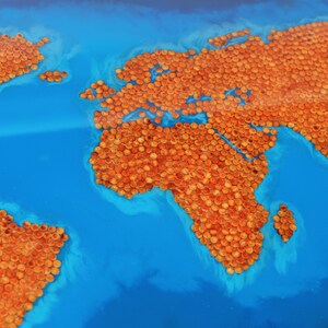 May include: A world map made of orange and brown round objects on a blue background.