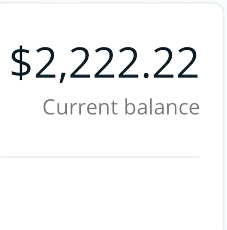 May include: The image shows the text "&pound;2,222.22" in a bold, black font, with "Current balance" in a smaller, grey font underneath. The background is a plain, light colour.