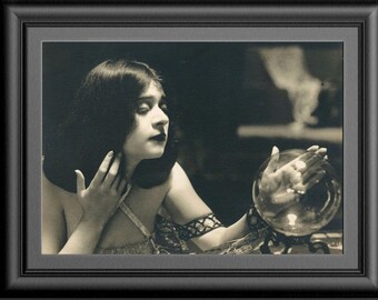 May include: A woman with long dark hair gazes into a crystal ball, her hand resting on the surface. The image is in black and white, creating a vintage feel.